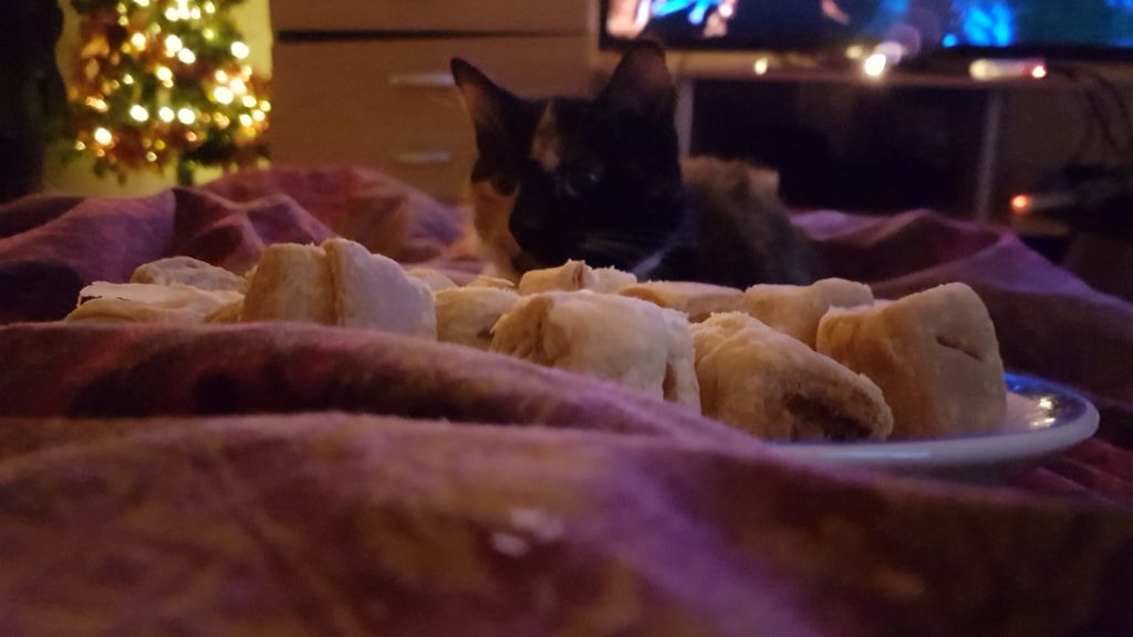 A plate of sausage rolls with onion and apple, with our cat Luna and the Christmas tree just in focus in the background