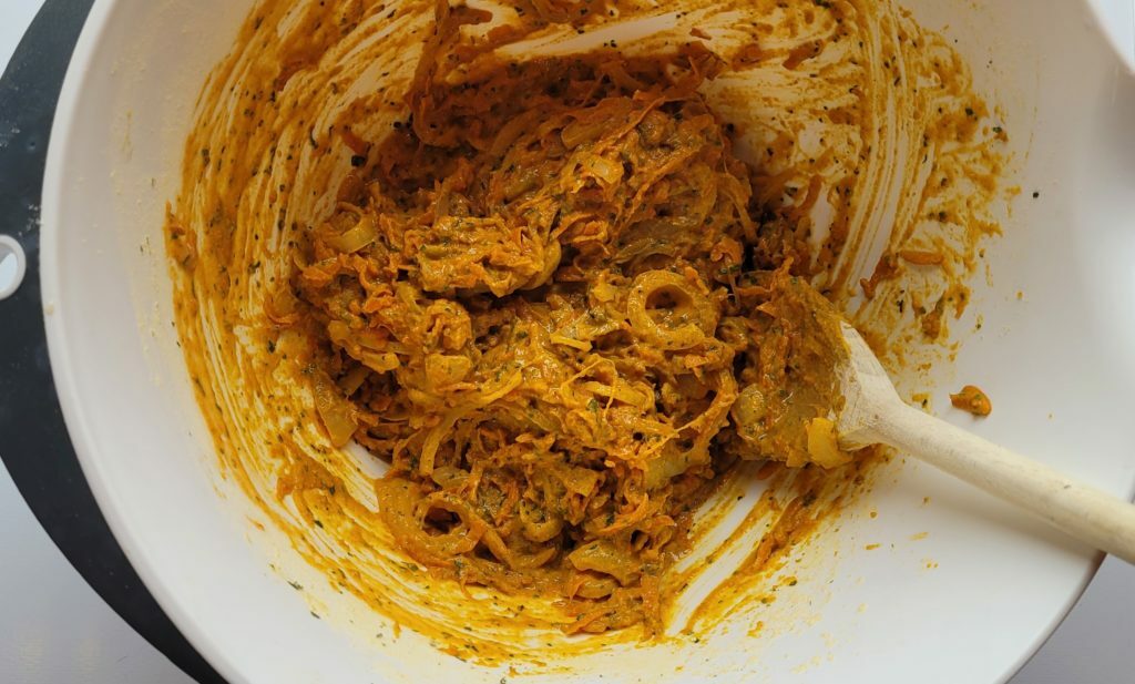 A large mixing bowl with the onion and carrot bhaji batter and a wooden spoon